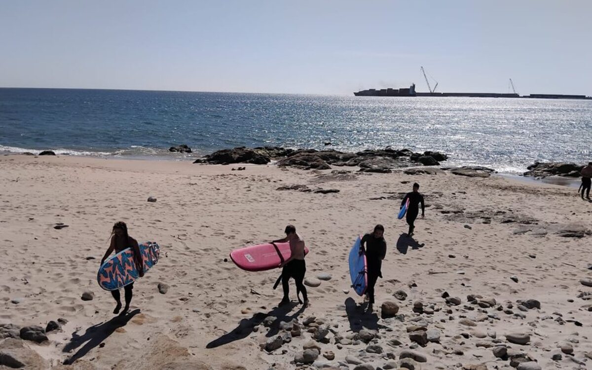 Pessoas a chegar à praia com pranchas, antes da sessão
